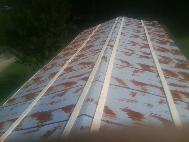 Rusted metal roof panels with new wood purlins before replacement — Storm Damage Roof Repair in Cave Springs by Roofing Brothers