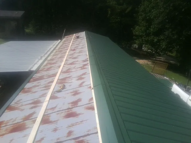 Old rusted panels beside newly installed green metal roofing — Wind Damage Roof Repair by Roofing Brothers in Cave Springs