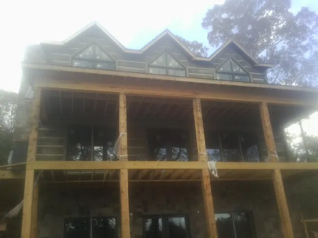 Dormers and porch framing on a large log home under construction — Roof Coating work by our crew in Cave Springs