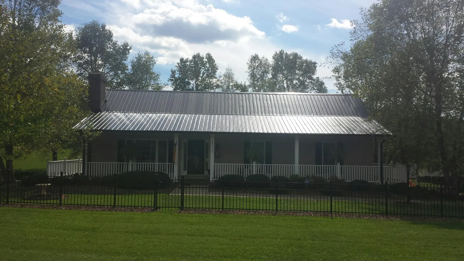 Gray metal roof on a brick ranch with a full width front porch — Gutter Guard Installation work by our crew in Cave Springs