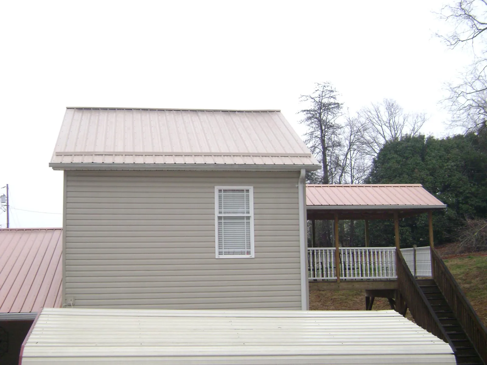 Tan metal roofs on a two story addition and attached porch, from a Roof Replacement job in Cave Springs